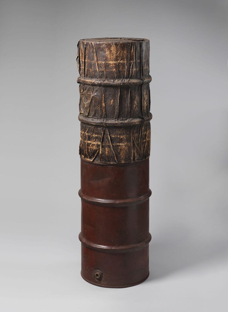 Two oil barrels one stacked on top of the other.