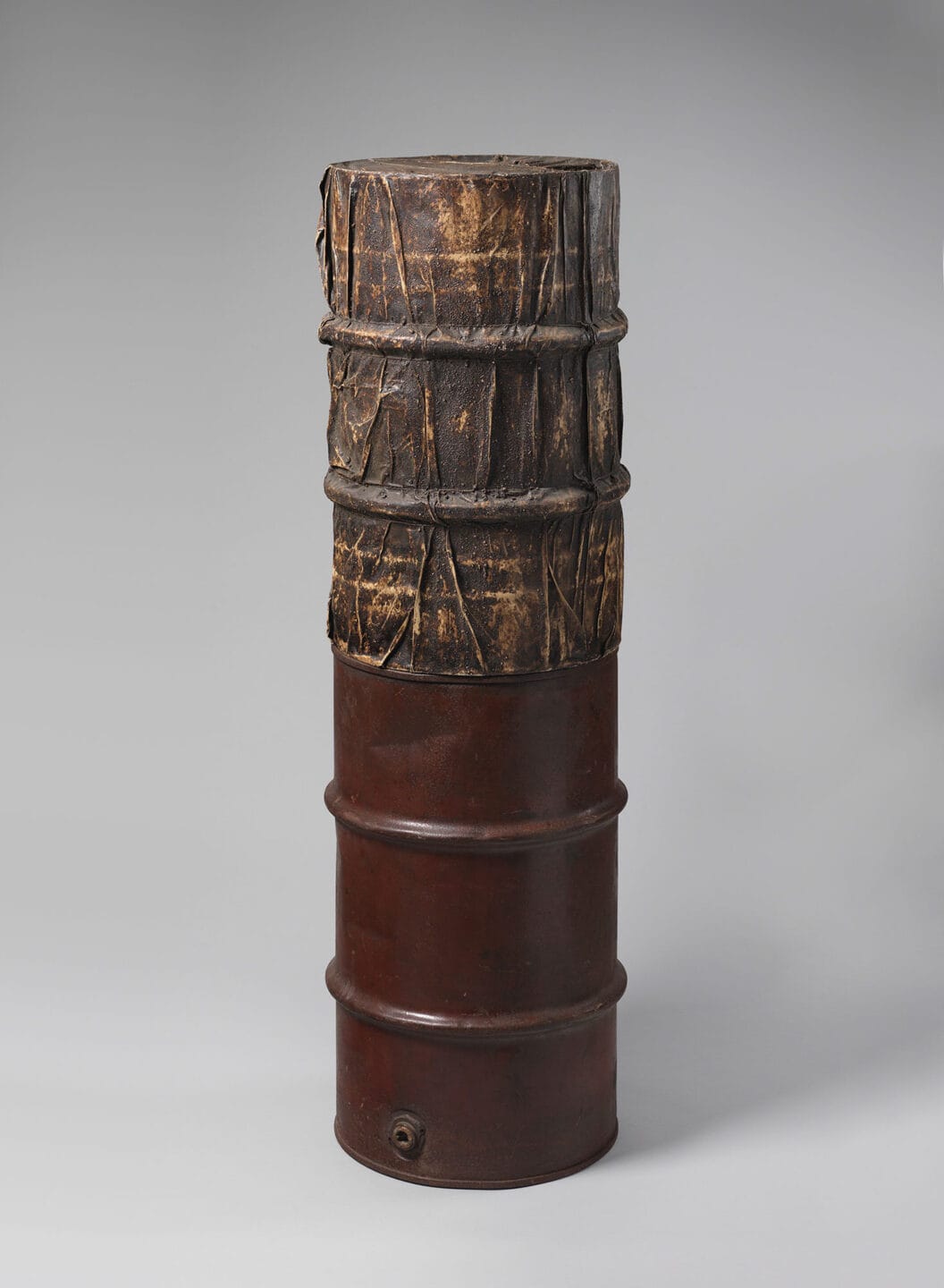 Two oil barrels one stacked on top of the other.