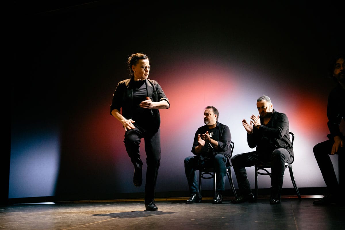 Soledad Barrio dancing as three seated musicians clap.