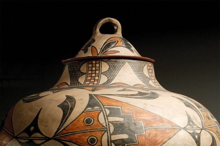 A close up of a pueblo pot against a black background.