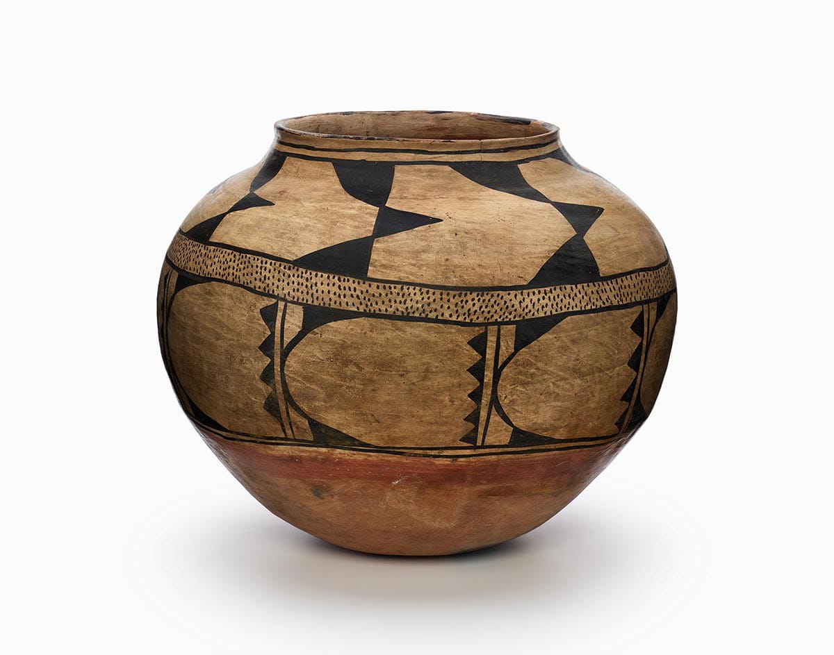 A Kewa storage jar, primarily painted brown, with a rust-orange bottom and black design.