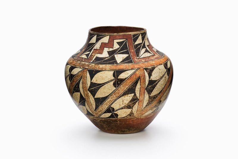 A four-color Acoma polychrome jar featuring white slip with black, red, and orange painted decoration.