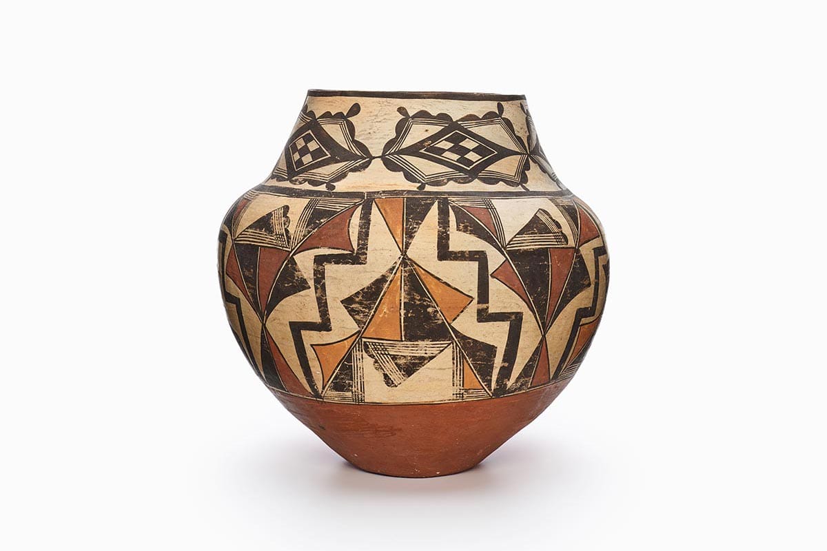 An Acoma jar decorated with black, beige, rust-brown, and red geometric patterns.