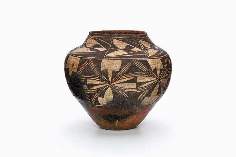 A Zia pot painted brown, black, and beige, with two bands of geometric designs.
