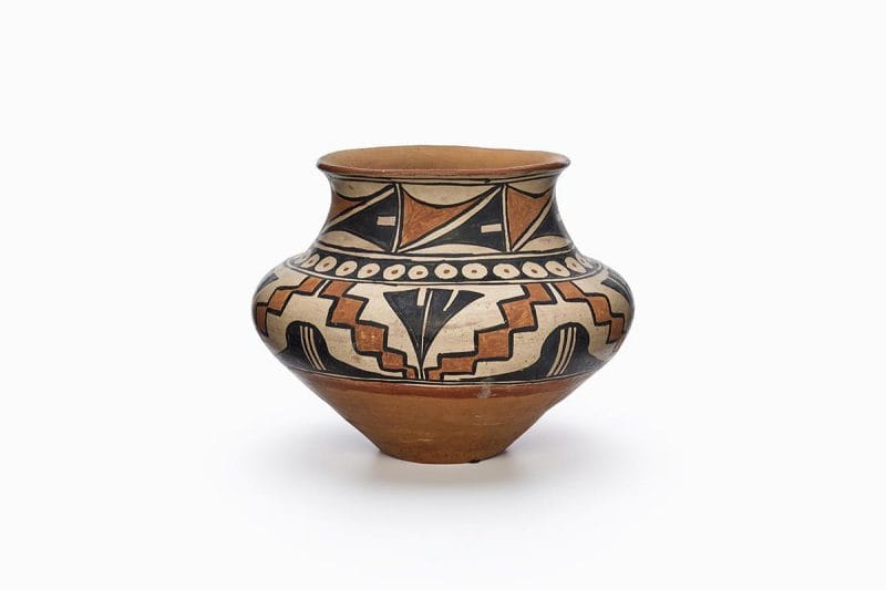 A three-color San Ildefonso polychrome pot featuring white slip with black and red painted decoration.