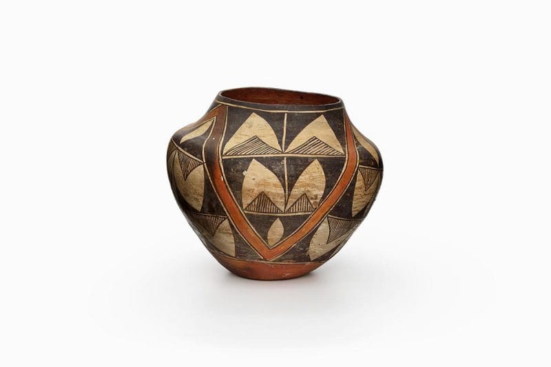 A three-color Acoma polychrome pot features cream slip with black and orange painted decoration.