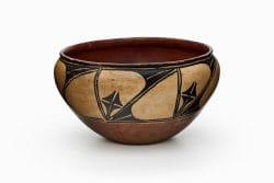 A beige and brown ceramic Kewa dough bowl painted with a black design composed of oval elements.