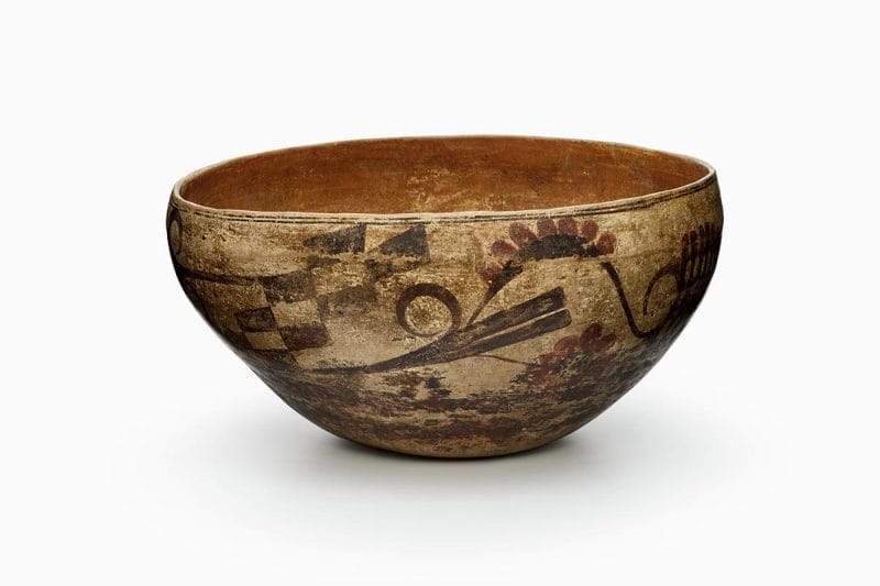 An Acoma bowl with checkered design and floral patterns in brown and red.