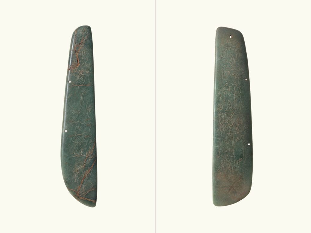 A comparison of two objects: an engraved half-celt in Maya style, and a half-celt with an intricately engraved figure with a headdress in Maya style.