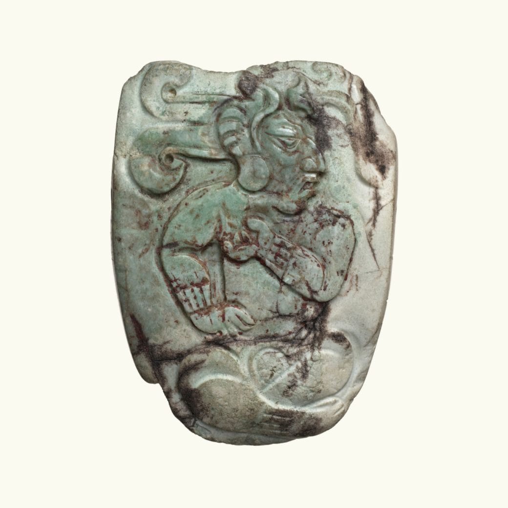 A jade pendent with a seated dignitary carved onto it.