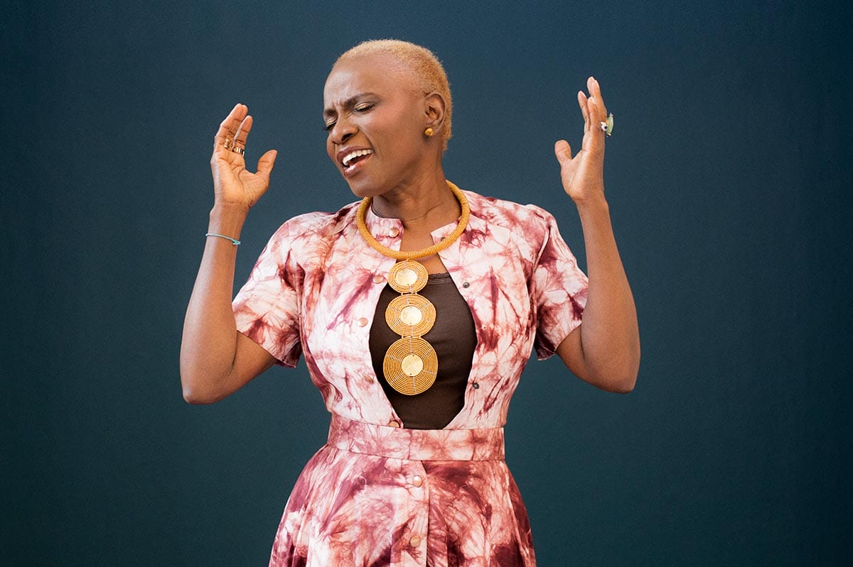 Angélique Kidjo singing with her hands raised.