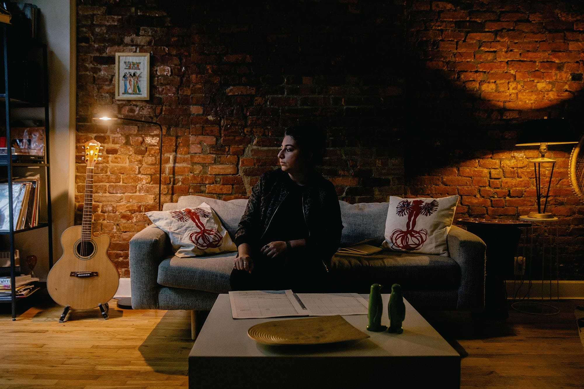 Arooj Aftab sitting on a couch looking off to the side.