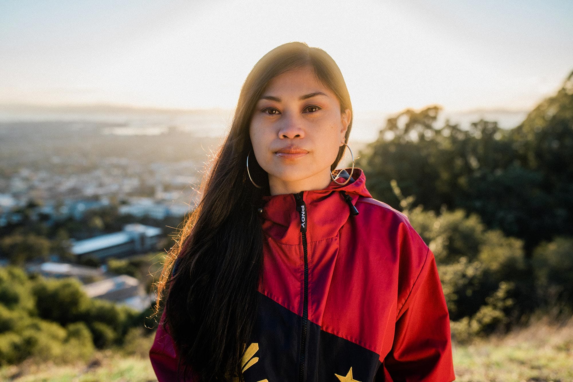 Ruby Ibarra in a red and black coat on the hills of San Francisco Bay Area.
