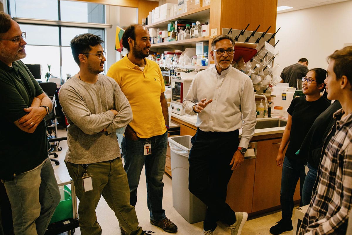 Alejandro Sánchez Alvarado talks with colleagues in his lab.