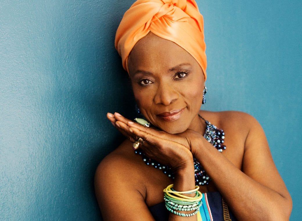 Angélique Kidjo with her hands pressed together and framing her face.