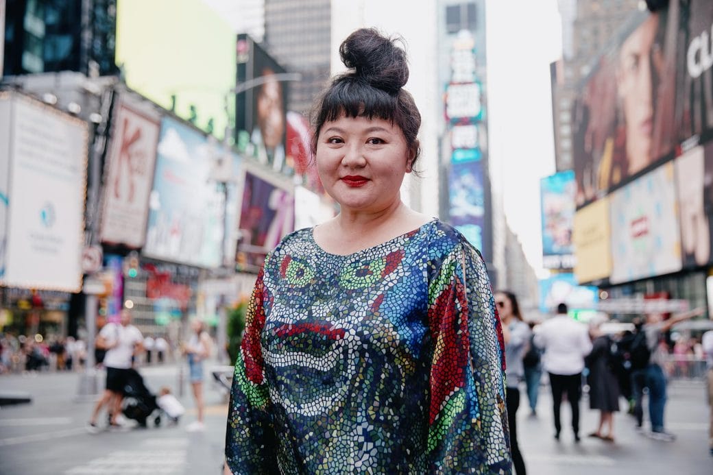 Du Yun in a colorful dress standing in Times Square.