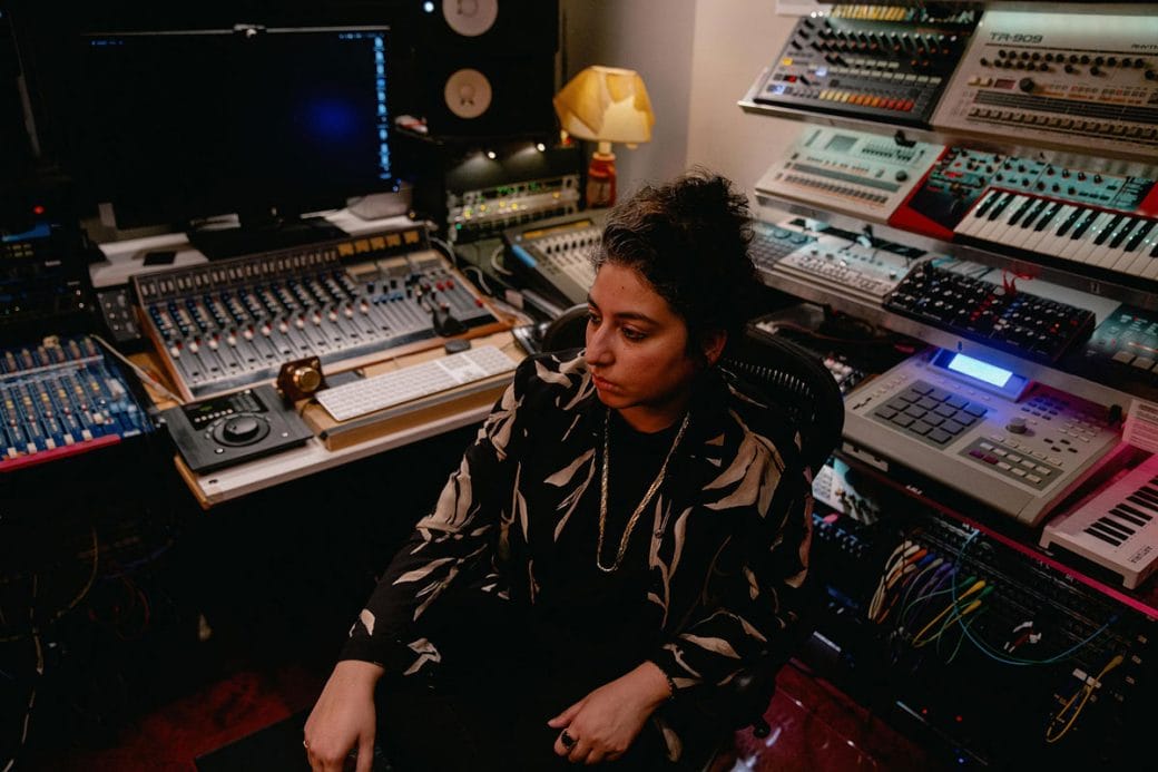 Arooj Aftab sitting in a studio surrounded by recording equipment.