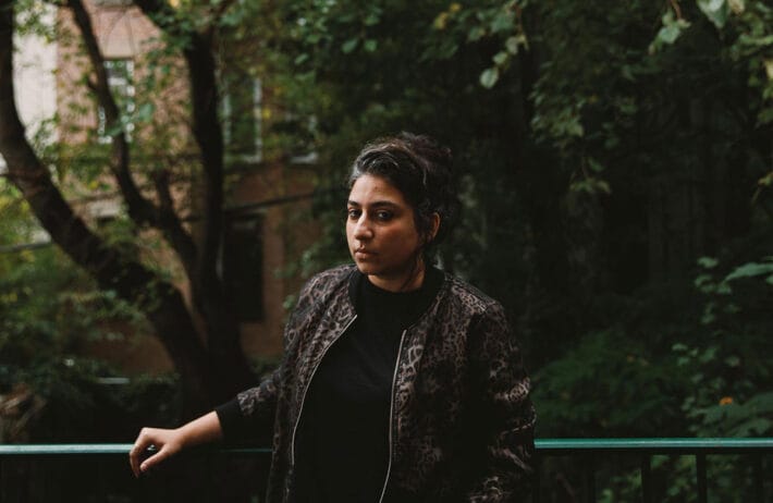 Arooj Aftab framed by green trees.