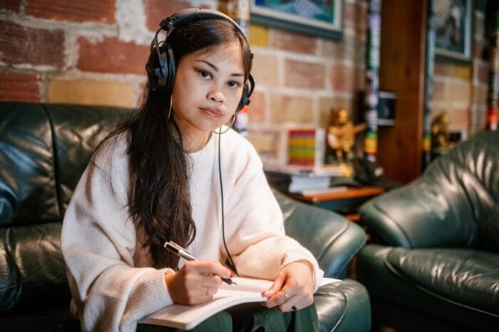 Ruby Ibarra sits on her couch writing and listening to music.