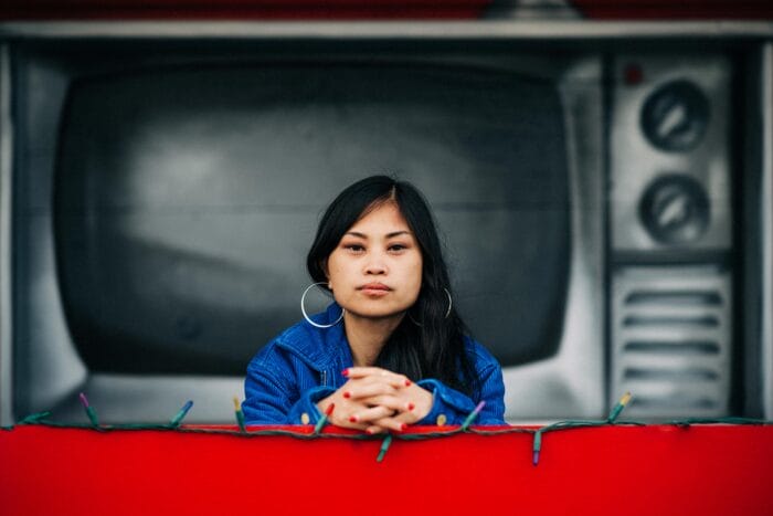 Ruby Ibarra stands in front of a mural of a old television.