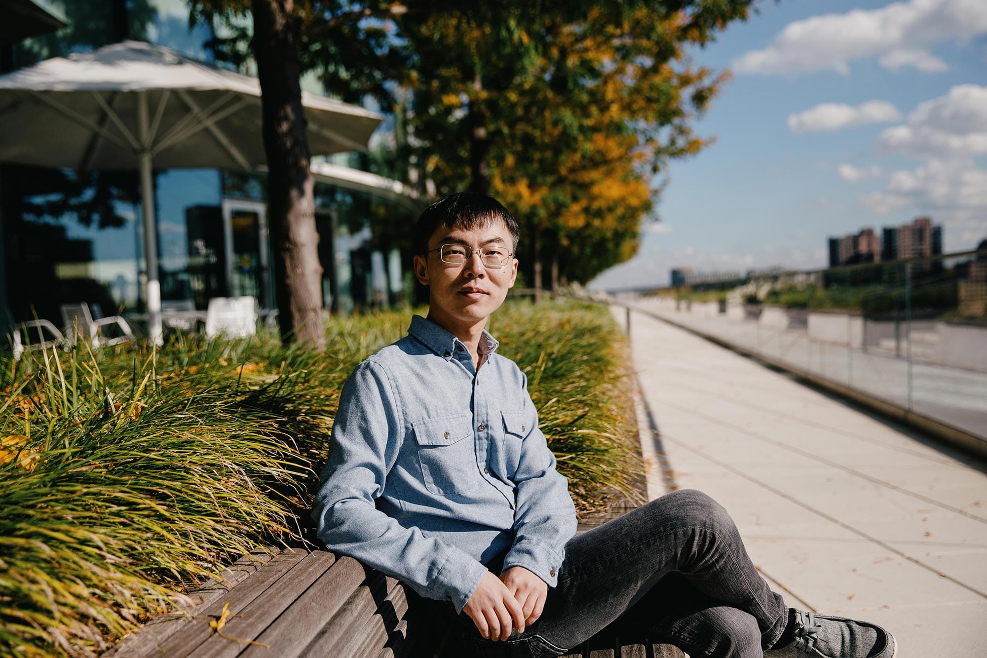 Shixin Liu sitting on a bench next to a path.