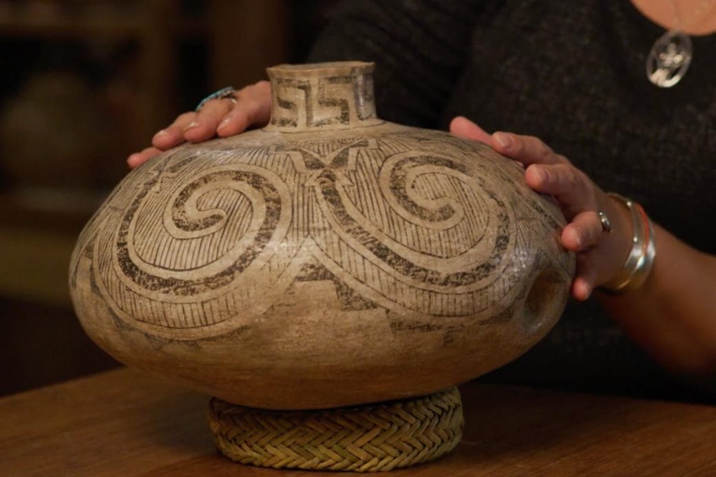 A contributor touching a Mogollon-Ancestral Puebloan jar with a divet visible.