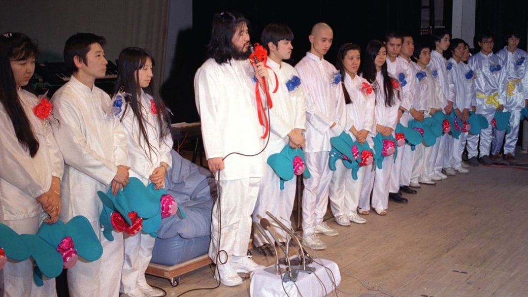 Members of Aum Shinrikyo all dressed in white holding blue headwear.
