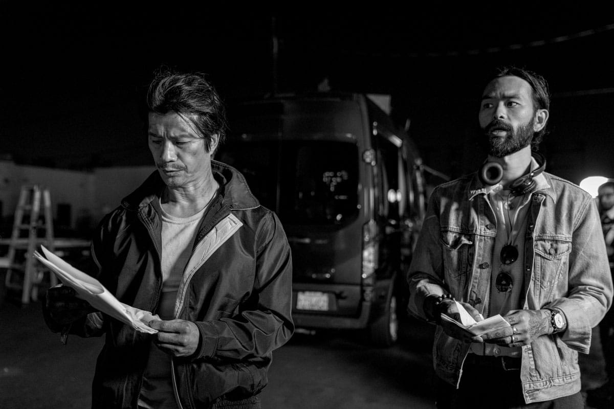 Sing J. Lee and a colleague on set holding scripts.