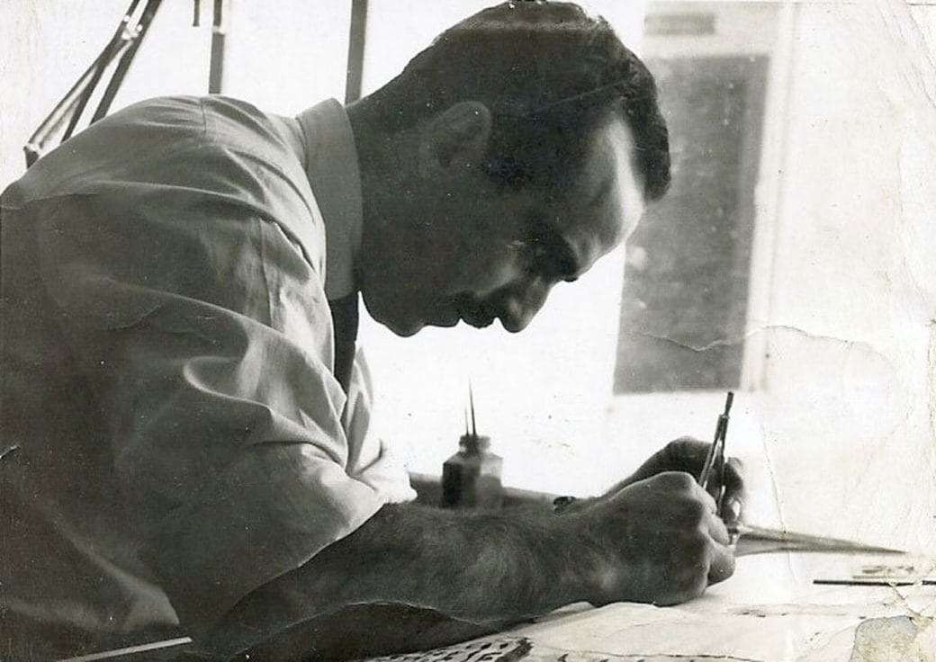 A black-and-white photograph of Roger Zmekhol writing.