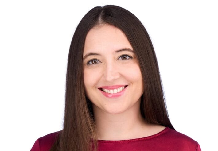 A portrait of Gerta Hoxhaj smiling and wearing a red shirt.