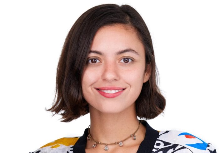 A portrait of Maryam Turkey smiling and wearing a necklace made with mixed-materials.