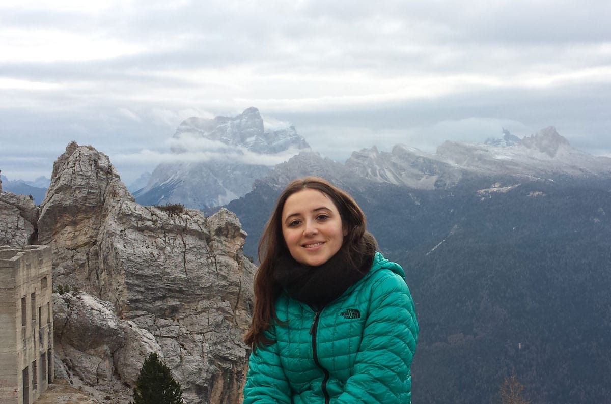 Gerta Hoxhaj smiles for a photo in front of vast snowy mountains.