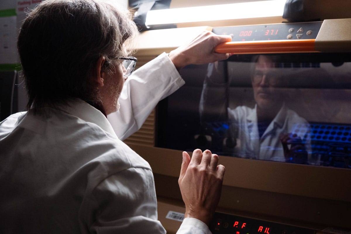 Luciano Marraffini looks at his reflection in the machinery in his lab.