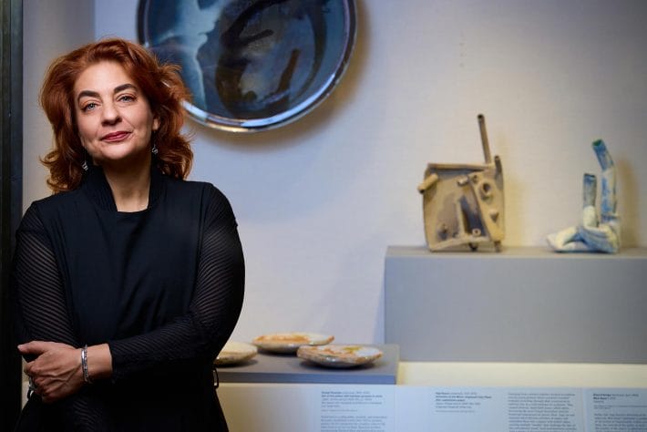 Monika Bincsik standing in front of an art exhibition display case.
