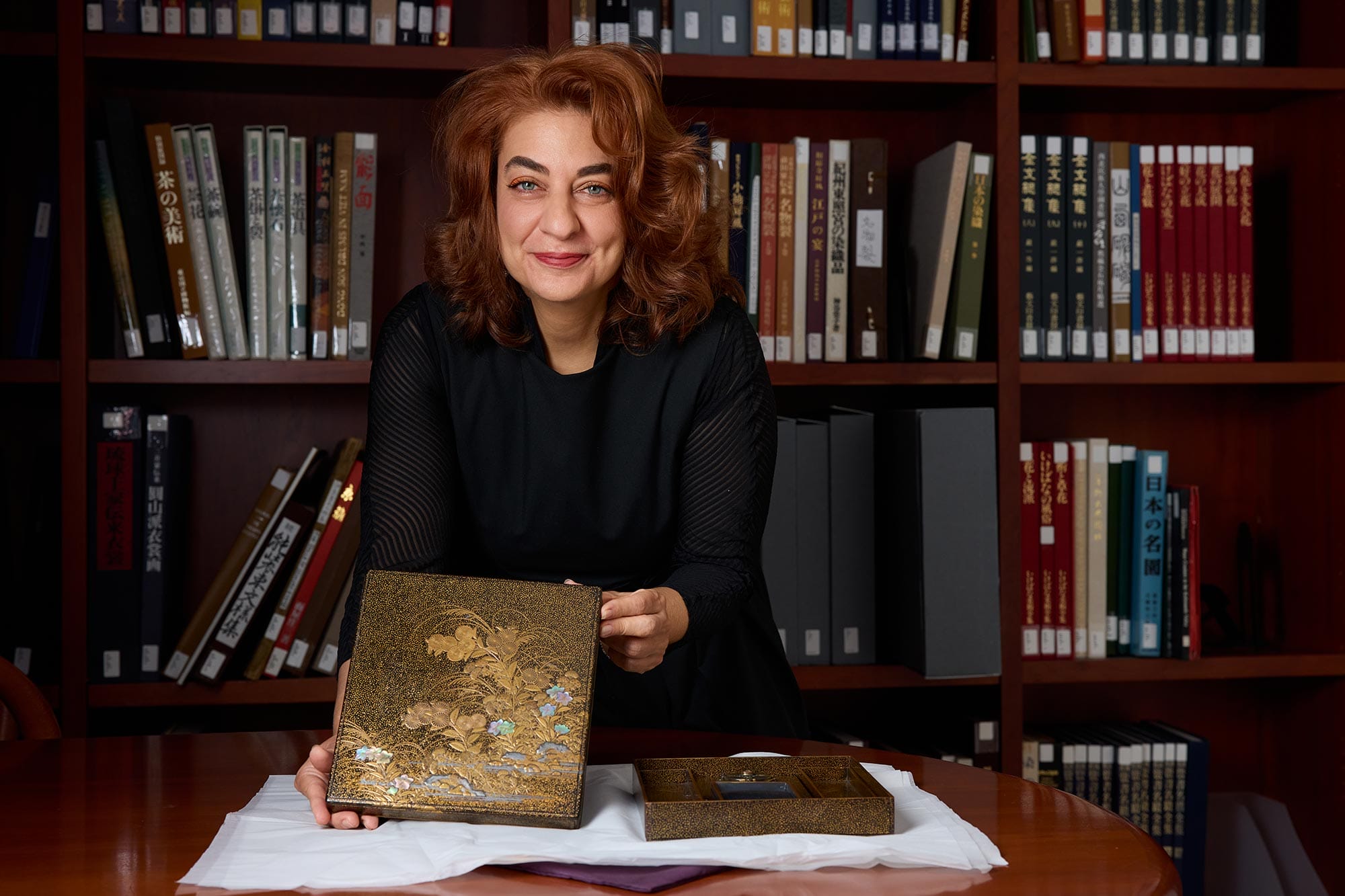 Monika Bincsik holding up a work of art on a table.