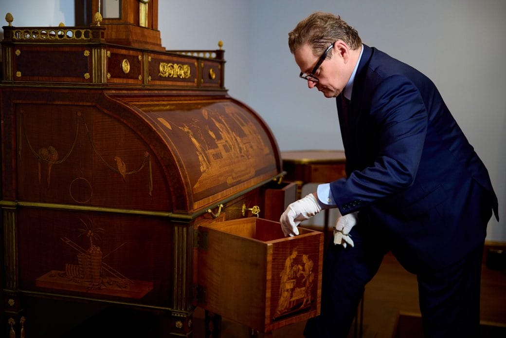 Wolfram Koeppe opening a compartment of an 18th century desk.