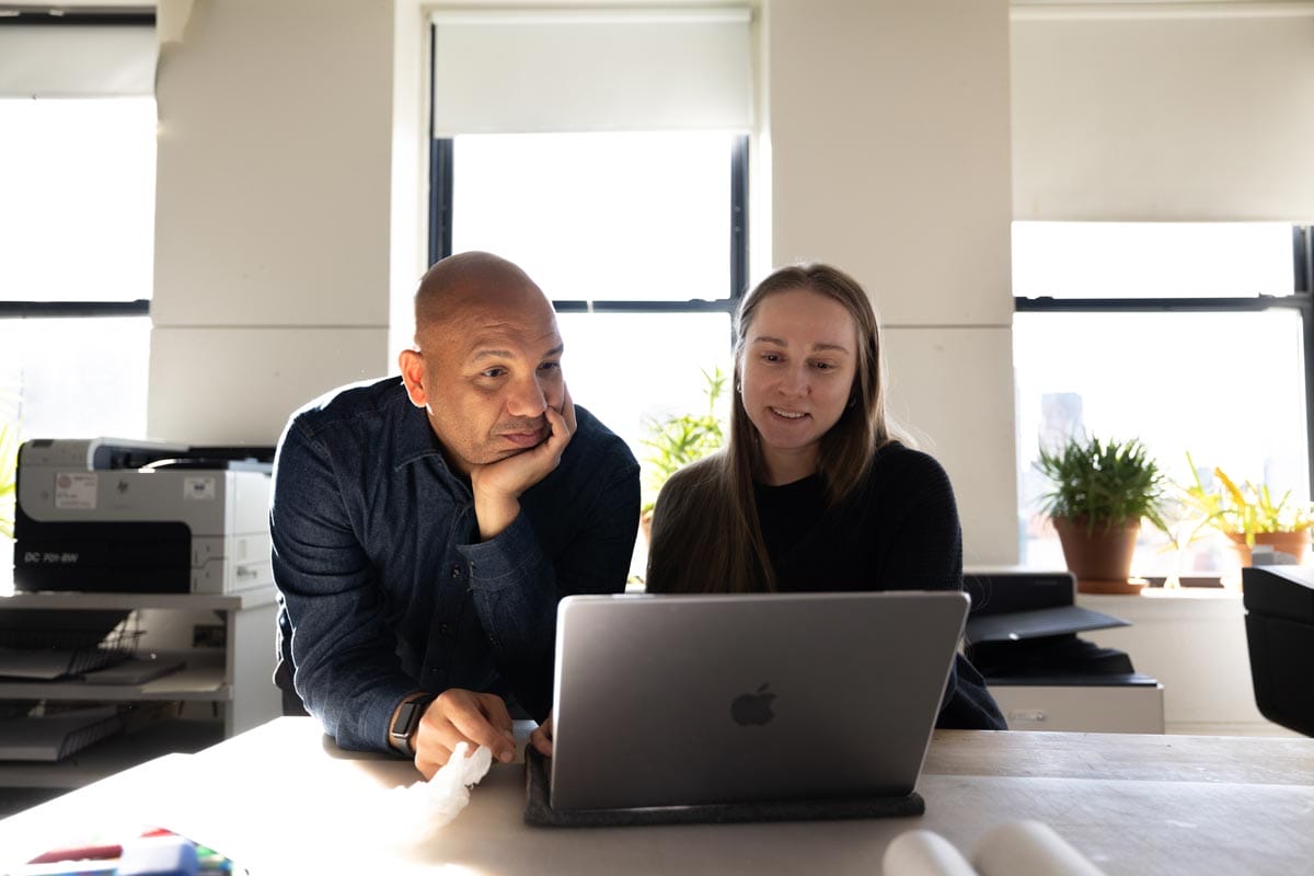 Ramon Tejada supervises a student as they work on a laptop.