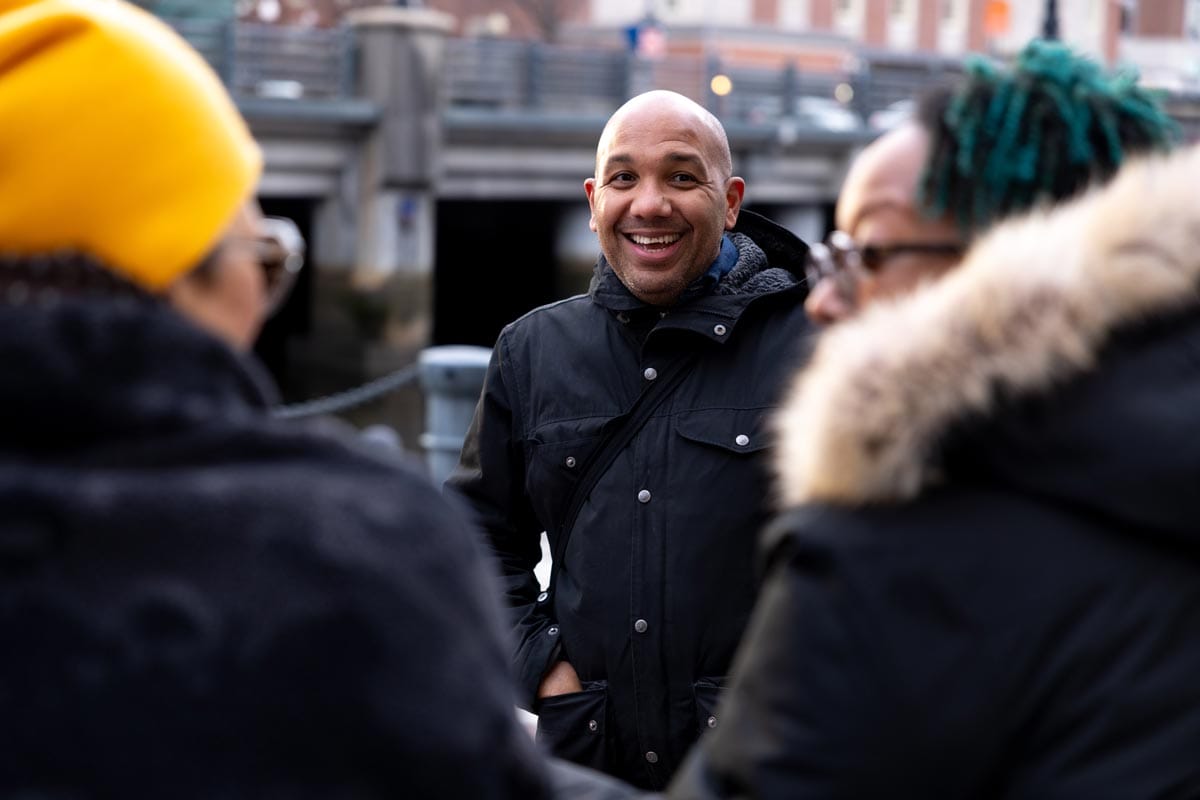 Ramon Tejada smiling as he stands outside and talks with two of his colleagues.