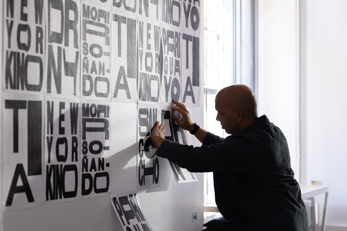 Ramon Tejada pasting prints of his typography up on a wall.