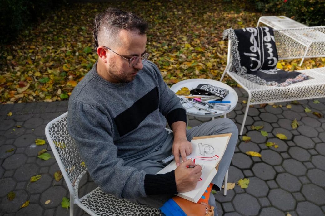 Wael Morcos sitting in a garden sketching in a notebook.