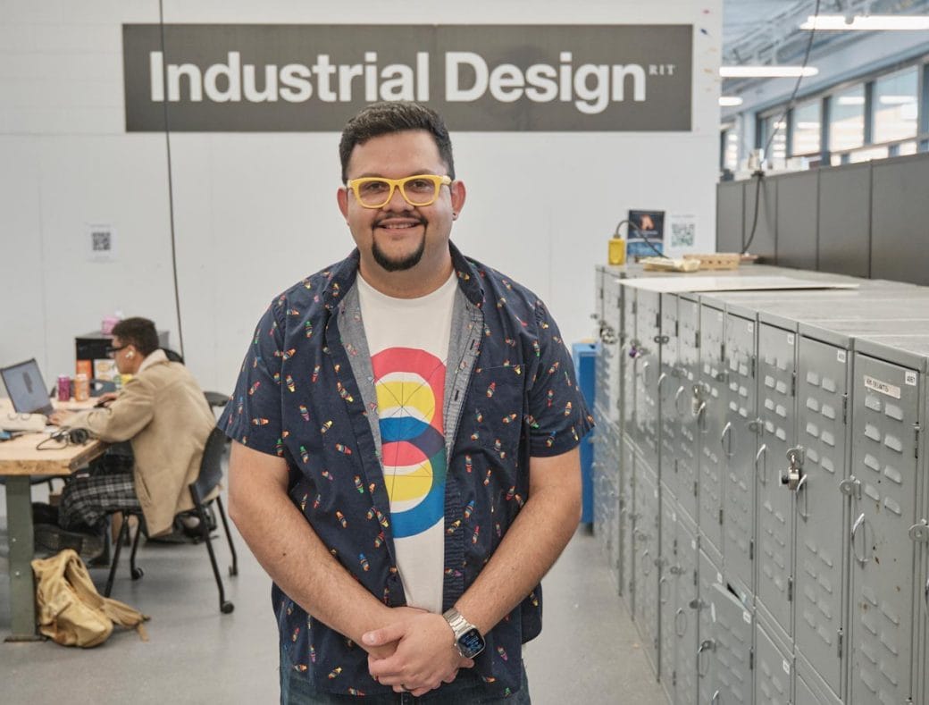 Juan Carlos Noguera standing and smiling in an Industrial Design studio/classroom.