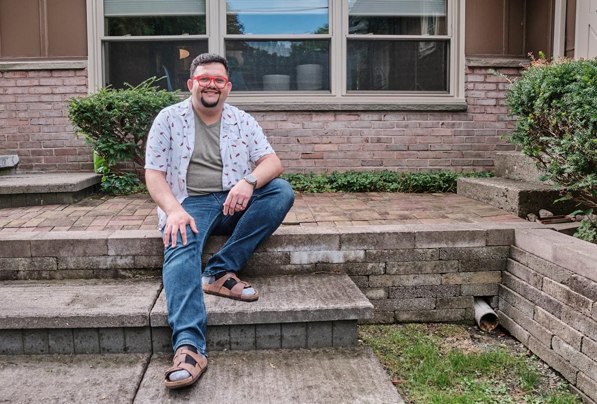 Juan Carlos Noguera smiles as he sits on the steps leading to his backyard.