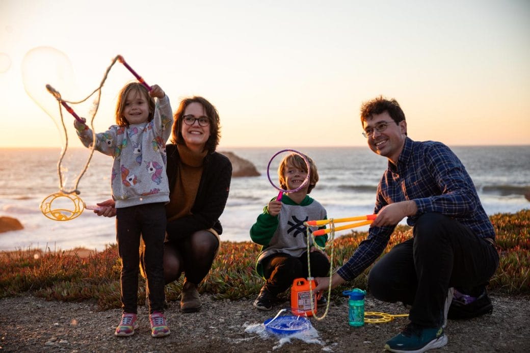 Tomasz Nowakowski, his wife, and two children playing with the bubbles on the beach.