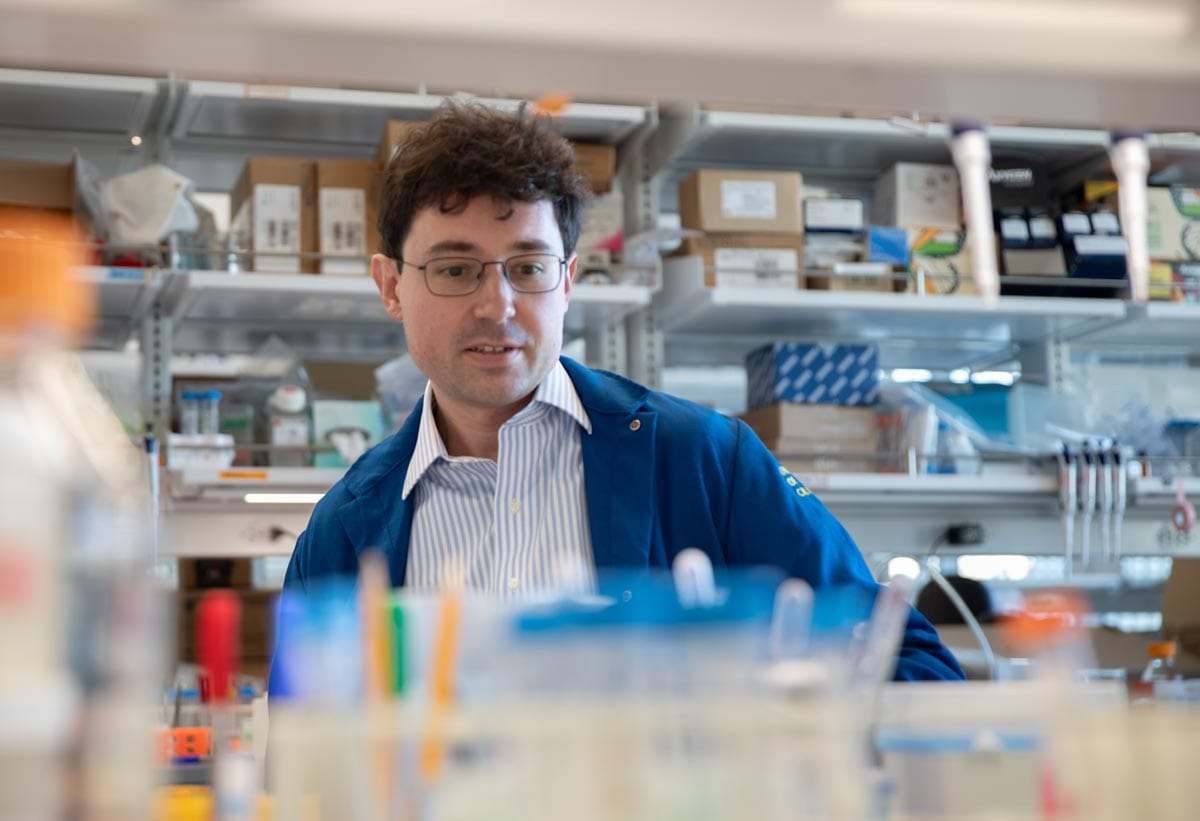 Tomasz Nowakowski, wearing a blue lab coat, at a lab bench.