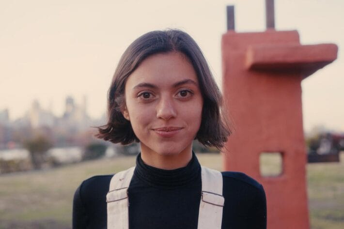 A portrait of Maryam Turkey in front of a large installation she designed.