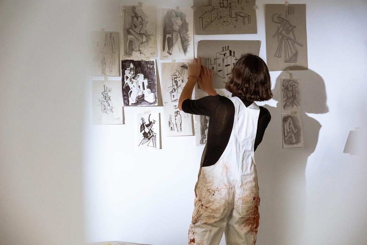 Maryam Turkey putting up drawings on the walls of her studio.