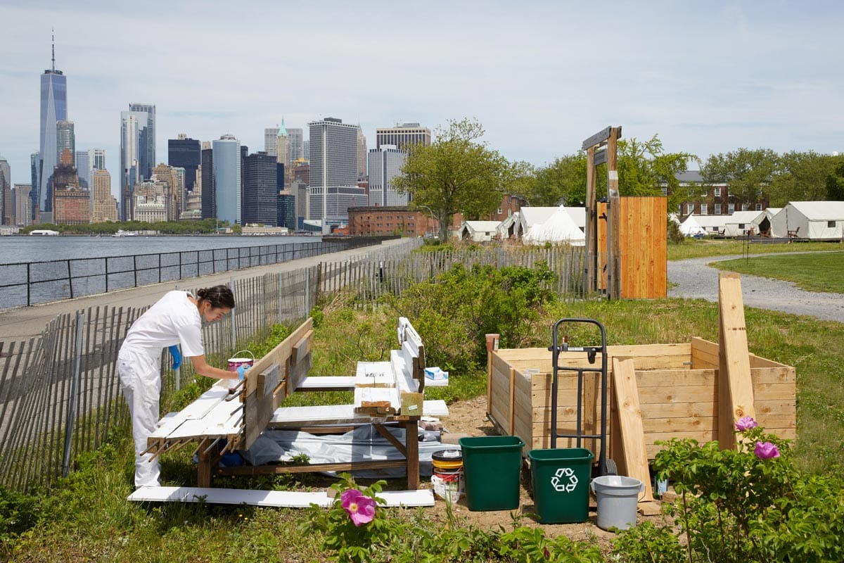 Maryam Turkey working on an outdoor installation with the New York City skyline behind her.