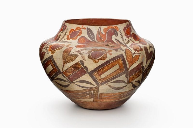 A four-color Acoma storage jar with a white slip with black, red, and orange painted decorations of parrots and flower forms.