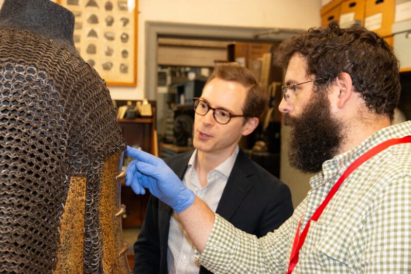 John Byck and his colleague inspecting the chain mail on a piece of armor.