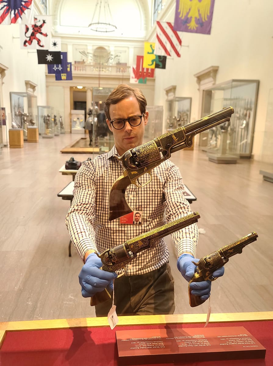 John Byck tinkering with the placement of firearms during the installation of an exhibit.